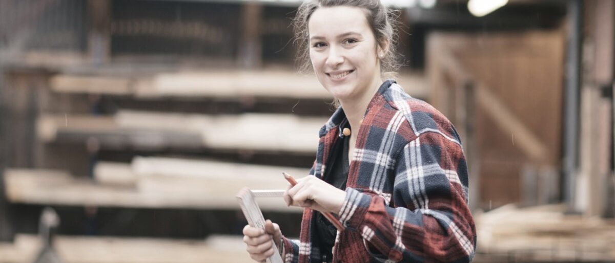 Junge Handwerkerinnen mit Zollstock in der Hand misst einen Holzbalken aus. Zimmerer - Bildung und Weiterbildung Schlagwort(e): Berufsbildung, Bildung, Bildungszentrum, Fortbildung, Lüneburg, Meister, Meisterkurs, Seminar, Seminare, TZH, Technologiezentren, Technologiezentrum, Unterricht, Weiterbildung, Zimmerer, ÜLU, Überbetriebliche Lehrlingsunterweisung