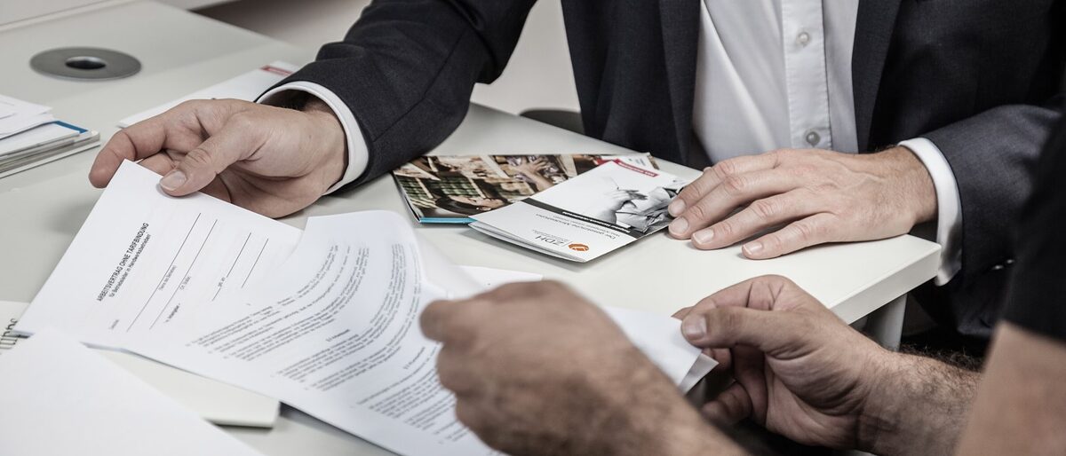 Ein Berater hilft einem Existenzgründer beim Ausfüllen der Formulare. Rechtsberatung, Recht, Beratung, Handwerkskammer, Büro, Ordner,