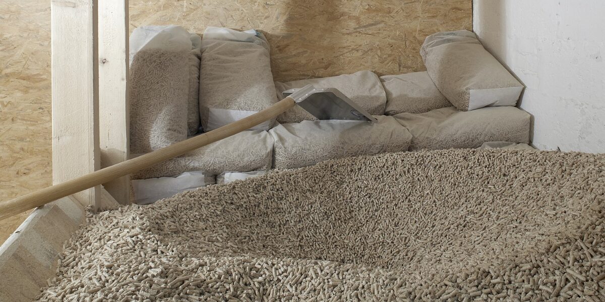 Vorne ein großer Haufen Holzpellets, dahinter eine Schaufel und abgepackte Beutel mit Holzpellets als Inhalt. holzpellets; lager; lagerung; klimaerwärmung; raum; nachhaltig; pelletheizung; heizen; co2; energieträger; holz; pellets; pelletlager; pelletlageraum; heizung; heizanlage; energie; energieversorgung; erneuerbare; energien; bio; wald; biowärme; keller; holzenergie; klima; nachwachsend; regenerativ; umwelt; umweltneutral; wärme; biologisch;