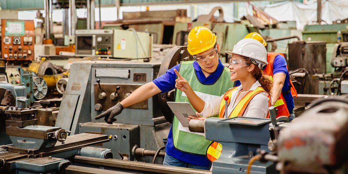 Handwerkerin zeigt einem Kollegen in der Werkstatthalle etwas auf einem iPad. Der Kollege zeigt auf die Werkbank, beide haben einen Sicherheitshelm auf. Mix race worker working together help each other to work in heavy industry machine wearing safty suit in factory production line.engineer with tablet coworking with team staff. Schlagwort(e): heavy duty, job, enjoy, smile, happy, duty, equipment, facility, Seifriz