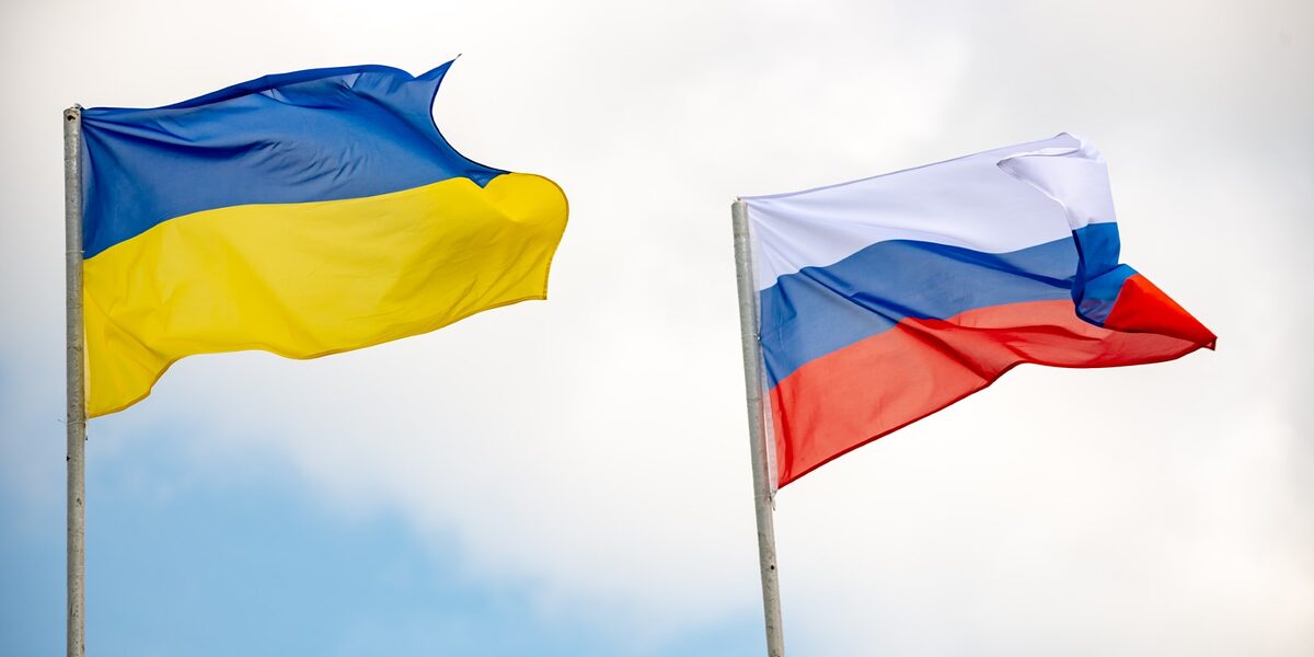 Flagen der Ukraine und Russland. Im Hintergrund blauer Himmel mit Wolken.