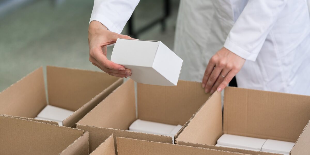Arbeiter verpackt Ware in Kartons.