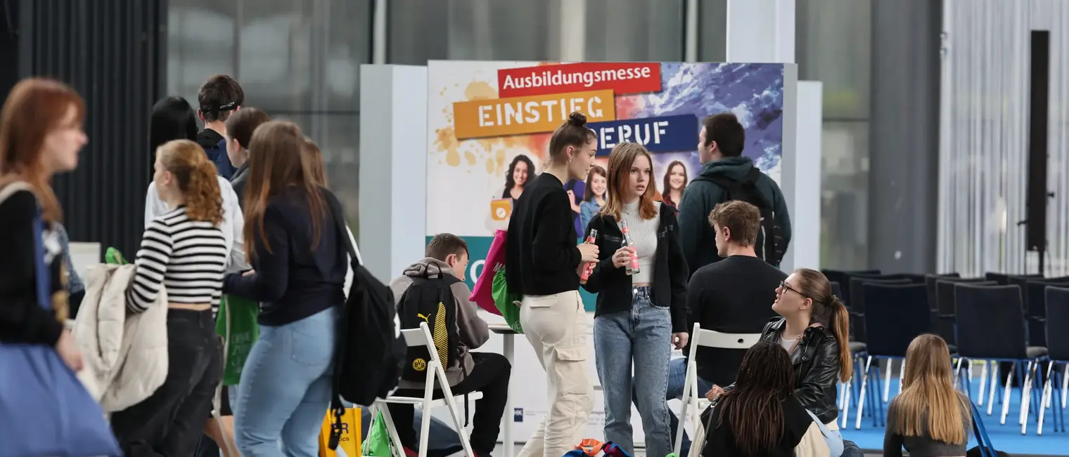 Gruppe von Jugendlichen stehen verteilt auf dem Messegelände.