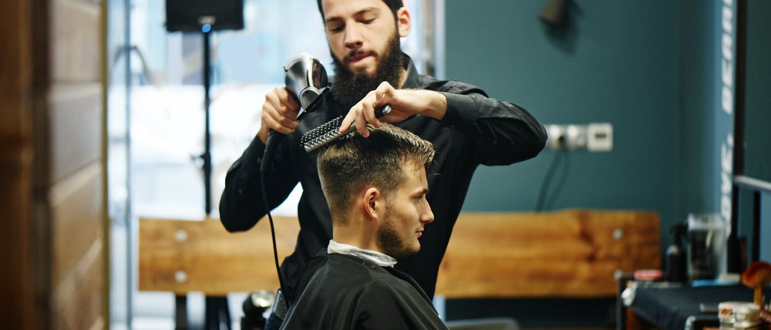Friseur schneidet einem Kunden die Haare.