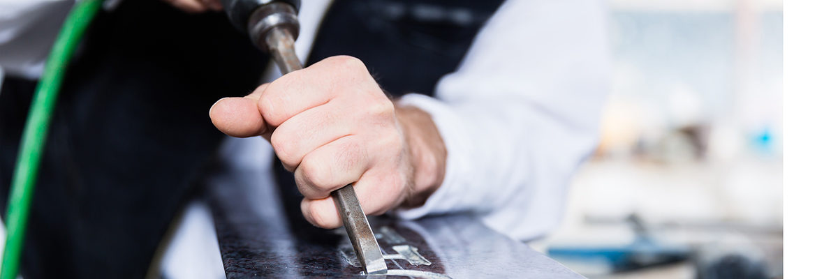 stonemason; man; stone carver; sculptor; stone; craft; handicraft; tombstone; gravestone; headstone; industrial; natural stone; sculpture; carve; cut; treat; handle; men; work; labour; workplace; workshop; handwork; art; artisan; design; style; workpiece; occupation; job; career; tool; chisel; compressed air; Gravure; engraving; inscription; pneumatic; precision; ornament; flourish; indoor; factory; factory hall; building; people; Caucasian; craftsman; handyman; workwear; garb; steinmetz; mann; handwerk; grabstein; industriell; grabmal; hauen; bearbeiten; beruf; bildhauer; stein; naturstein; plastik; skulptur; mnner; arbeit; arbeitsplatz; werkstatt; kunst; kunsthandwerk; gestaltung; handarbeit; werkstck; beschftigung; karriere; anstellung; ausbildung; werkzeug; meiel; druckluft; gravur; inschrift; pressluft; pneumatisch; feinarbeit; przision; verzierung; innen; drinnen; werkhalle; betrieb; menschen; leute; handwerker; arbeiter; arbeitskleidung; handwerkertracht; europisch;
