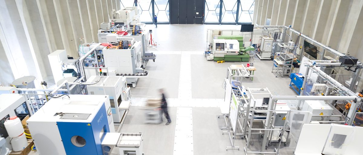 An der ETA-Fabrik der TU Darmstadt auf dem Campus Lichtwiese wird unter Realbedingungen und im Originalmaßstab erforscht, wie sich durch intelligente Vernetzung aller Gebäude- und Produktionskomponenten Energie in der Industrie noch effizienter nutzen lässt. An dem interdisziplinären Forschungsprojekt, das vom Institut für Produktionsmanagement, Technologie und Werkzeugmaschinen (PTW) geleitet wird, sind Wissenschaftler aus den Bereichen Maschinenbau, Bauingenieurwesen und Architektur sowie Partnerunternehmen aus der Industrie beteiligt. Das Gebäude wurde im März 2016 eröffnet. Schlagwort(e): ETA-Fabrik, Forschung, Gebäude, horizontal, Innenaufnahme, Institut für Produktionsmanagement / Technologie und Werkzeugma, Maschinenbau, Versuchshalle